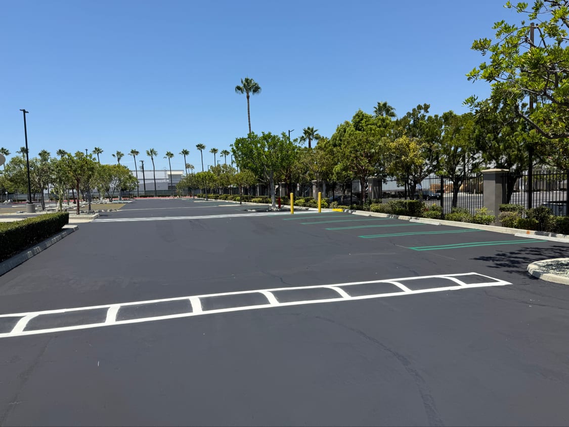 Fresh crosswalk bars and green markings on a newly sealed parking lot