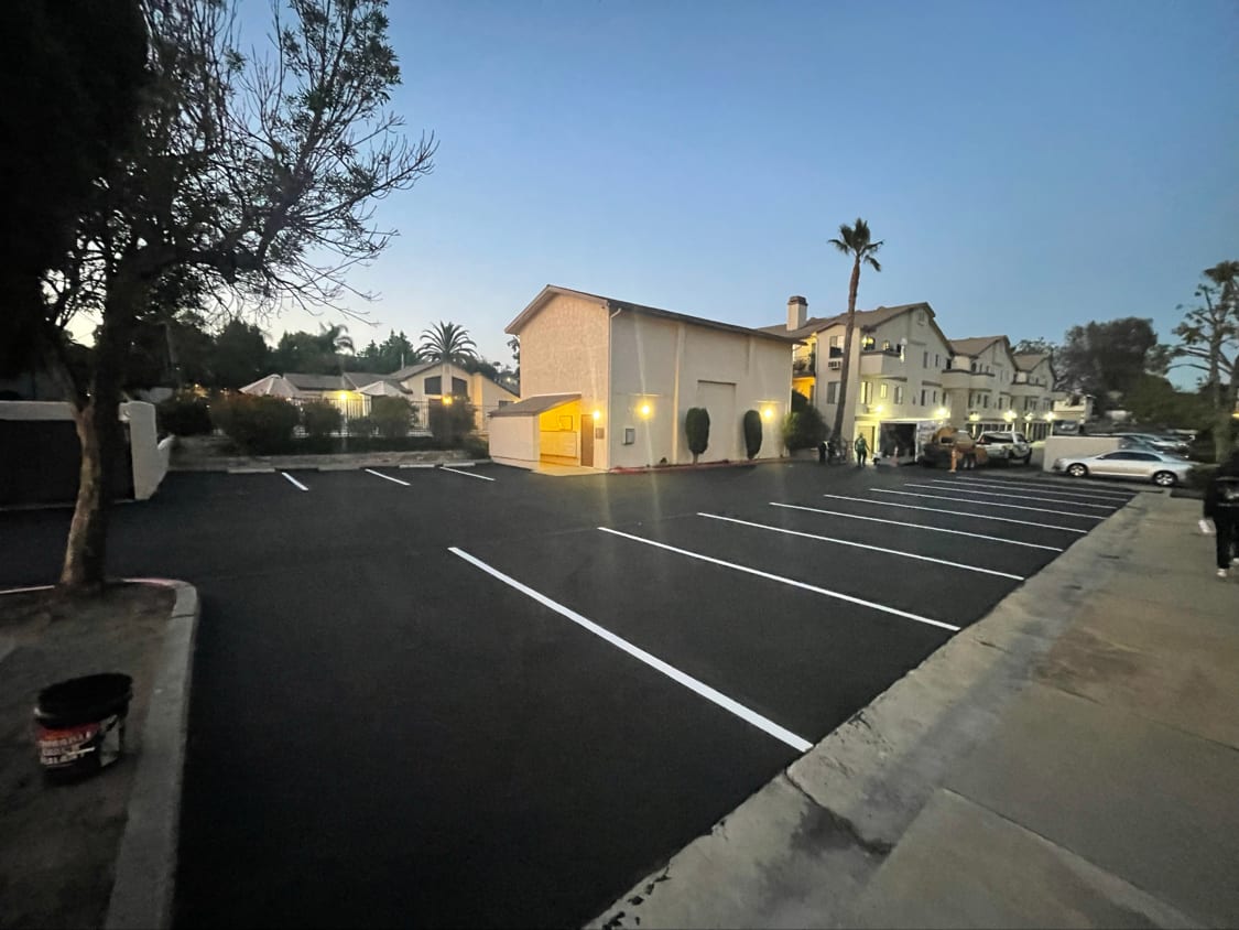 Resurfaced apartment parking lot with fresh white stall lines and a red fire curb