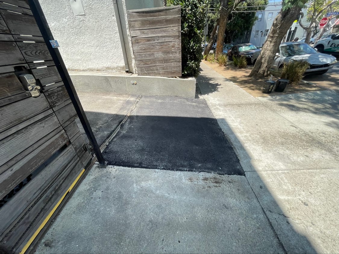 The same gated approach after full-depth asphalt repair, smooth and flush to the concrete